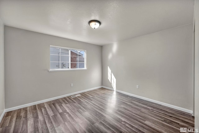 unfurnished room featuring a textured ceiling and dark hardwood / wood-style floors