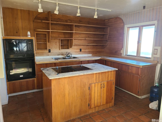 kitchen with sink, a kitchen island, wood walls, and black appliances