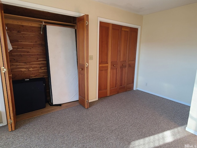 unfurnished bedroom featuring carpet floors, a closet, and wooden walls