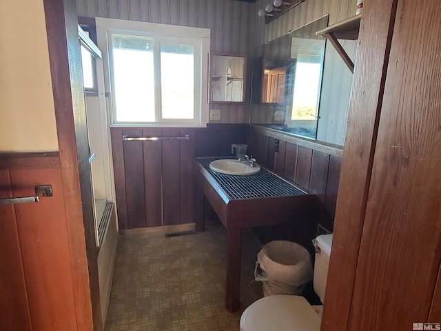 full bathroom featuring toilet, bath / shower combo with glass door, and sink