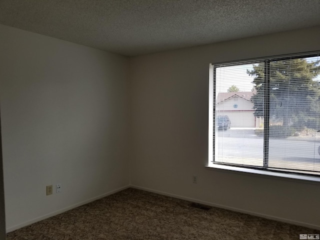 carpeted empty room featuring a textured ceiling