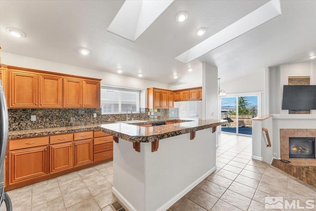 kitchen with backsplash, a fireplace, a breakfast bar area, and a wealth of natural light