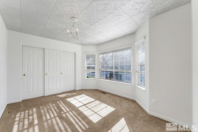 unfurnished bedroom featuring a closet, carpet floors, and a notable chandelier