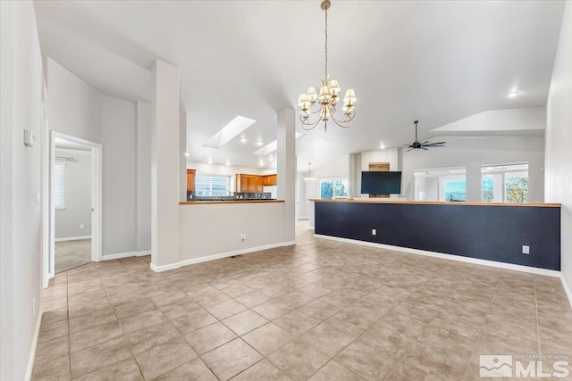 unfurnished living room featuring ceiling fan with notable chandelier, lofted ceiling with skylight, and light tile patterned flooring