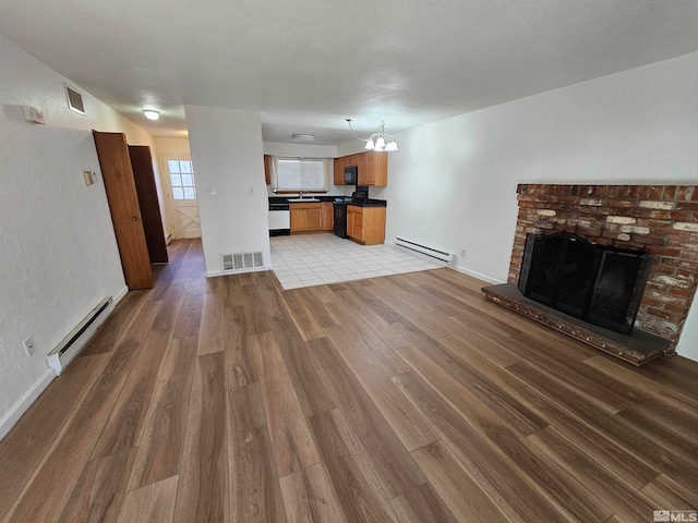 unfurnished living room featuring a notable chandelier, wood-type flooring, and a baseboard radiator