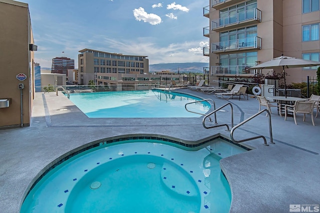 view of pool with a mountain view, a community hot tub, and a patio