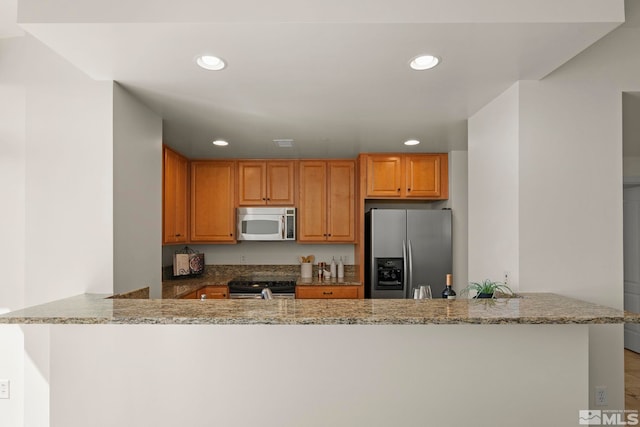 kitchen with kitchen peninsula, light stone countertops, stainless steel appliances, and light wood-type flooring