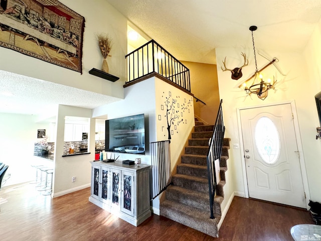 entrance foyer featuring wood-type flooring, a textured ceiling, and an inviting chandelier