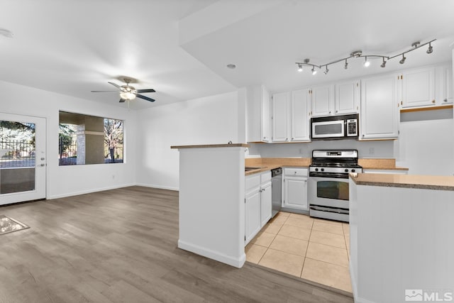 kitchen with kitchen peninsula, appliances with stainless steel finishes, ceiling fan, light hardwood / wood-style floors, and white cabinetry