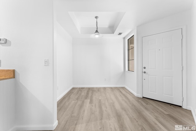 entrance foyer with light wood-type flooring and a tray ceiling