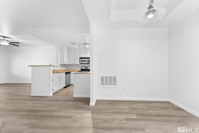 kitchen featuring appliances with stainless steel finishes, light hardwood / wood-style flooring, white cabinetry, and pendant lighting