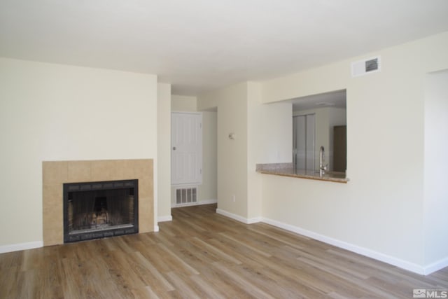 unfurnished living room featuring a fireplace, light hardwood / wood-style flooring, and sink