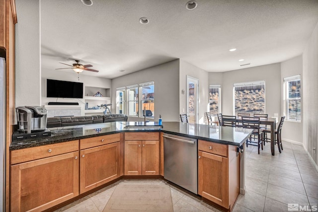 kitchen with sink, stainless steel dishwasher, ceiling fan, a textured ceiling, and kitchen peninsula