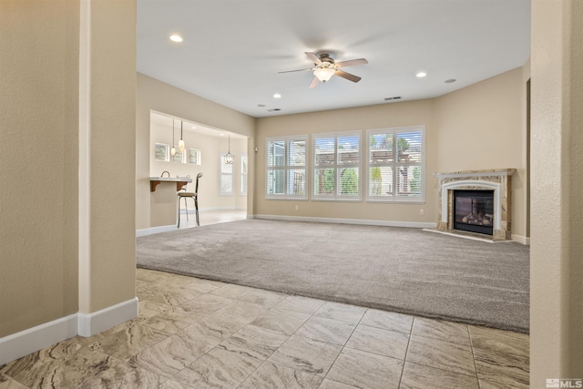 unfurnished living room with ceiling fan, light carpet, and a high end fireplace