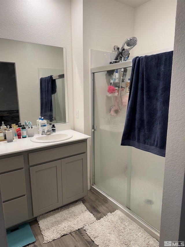 bathroom featuring wood-type flooring, vanity, and a shower with shower door