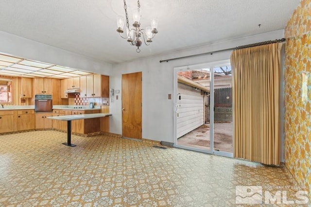 kitchen featuring black oven, light brown cabinets, and a chandelier