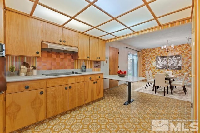 kitchen with black electric stovetop, backsplash, and an inviting chandelier