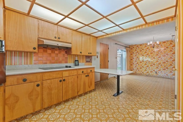 kitchen with decorative backsplash, black electric stovetop, and a notable chandelier