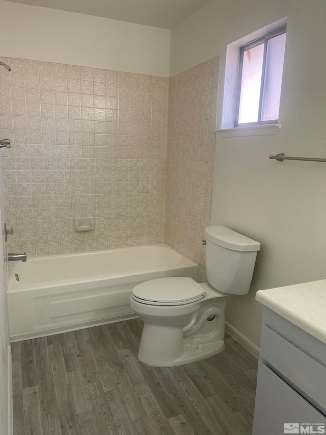 full bathroom featuring hardwood / wood-style flooring, vanity, toilet, and tiled shower / bath