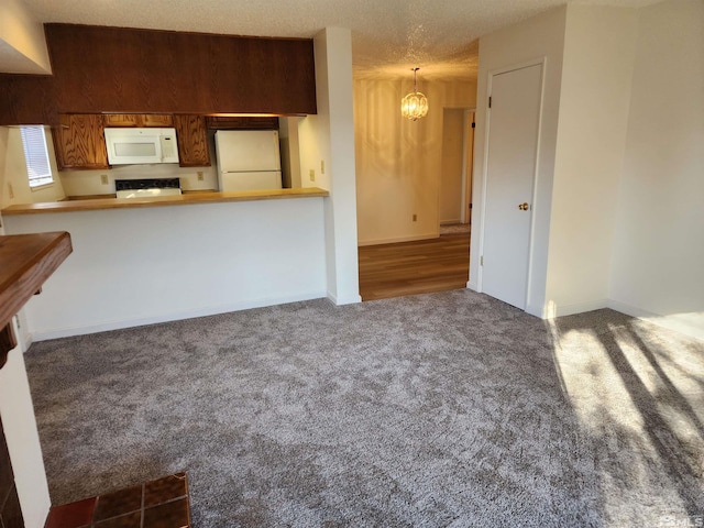 kitchen with kitchen peninsula, a textured ceiling, white appliances, carpet floors, and hanging light fixtures