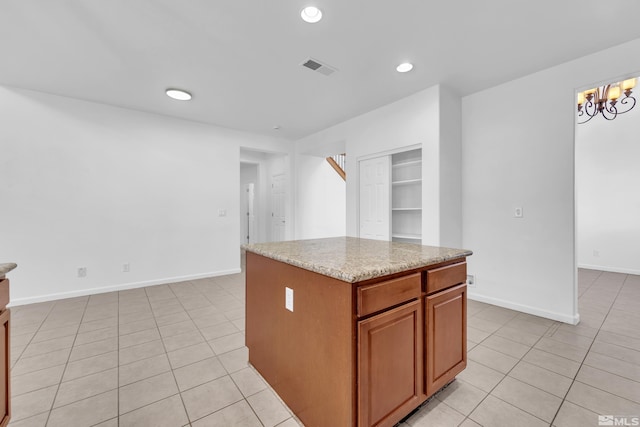 kitchen featuring light stone countertops, light tile patterned floors, an inviting chandelier, and a kitchen island