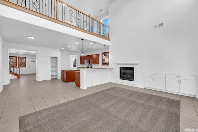 unfurnished living room with light tile patterned flooring and a high ceiling