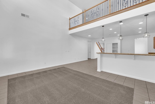 unfurnished living room with tile patterned flooring and a towering ceiling