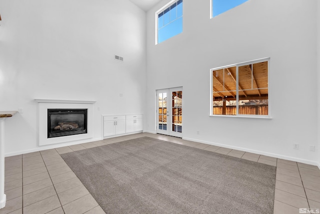 unfurnished living room featuring light tile patterned flooring and a high ceiling