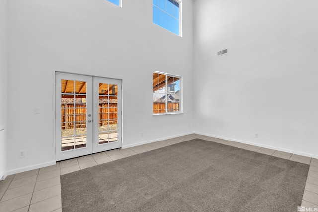 carpeted spare room featuring a high ceiling and french doors