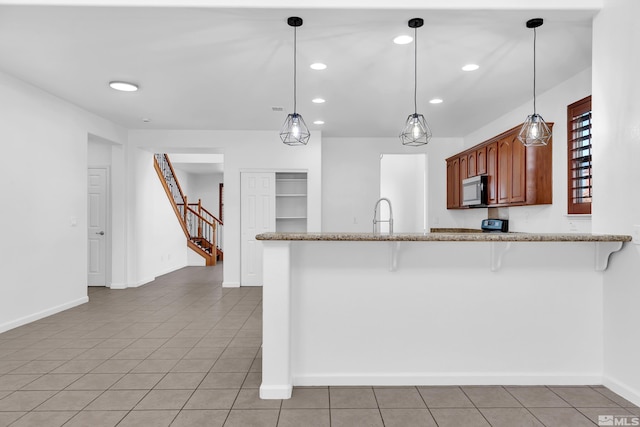 kitchen with pendant lighting, light tile patterned flooring, a kitchen bar, and kitchen peninsula