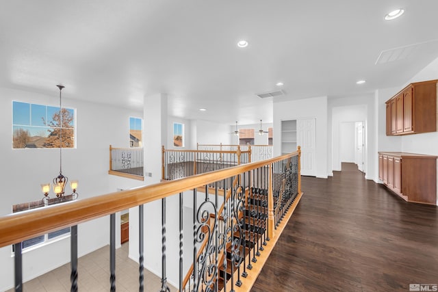 hall featuring dark wood-type flooring and an inviting chandelier