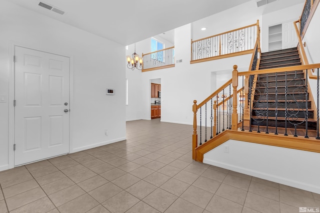 entrance foyer featuring tile patterned floors, a towering ceiling, and a notable chandelier