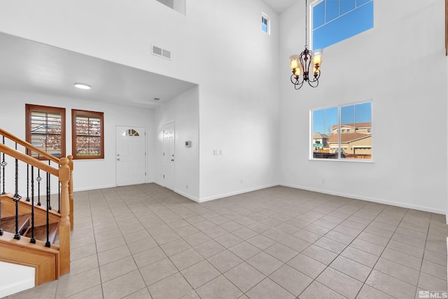 unfurnished living room with light tile patterned floors, a towering ceiling, and a notable chandelier