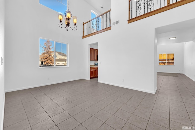 unfurnished living room featuring light tile patterned floors, a towering ceiling, and a notable chandelier