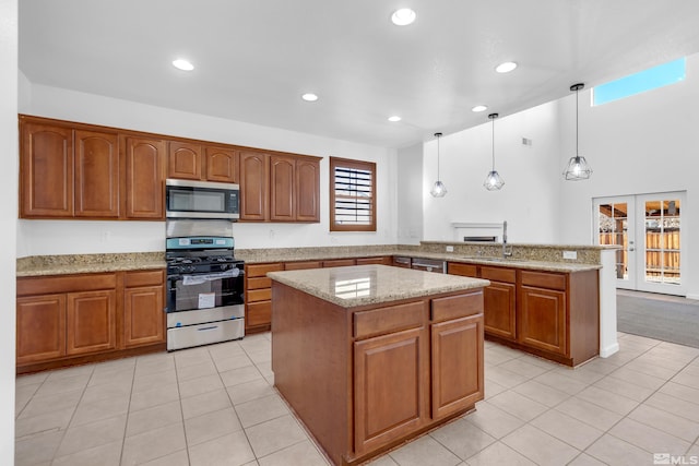 kitchen featuring decorative light fixtures, a kitchen island, light tile patterned flooring, and stainless steel appliances