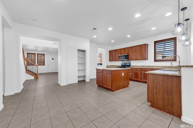 kitchen featuring black gas range oven, sink, pendant lighting, light tile patterned floors, and a center island