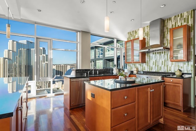 kitchen with a healthy amount of sunlight, a kitchen island, stainless steel appliances, and wall chimney range hood