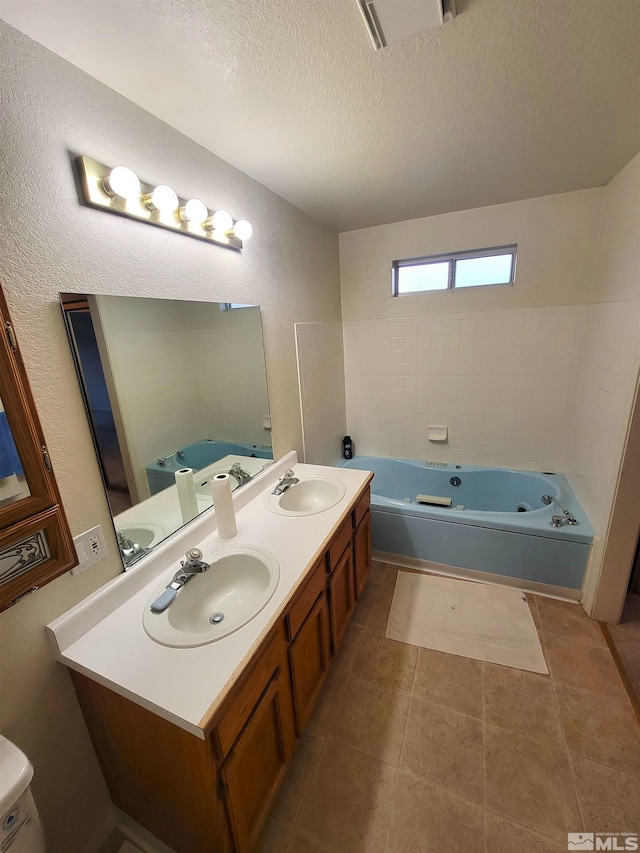 bathroom with tile patterned floors, a washtub, vanity, a textured ceiling, and toilet