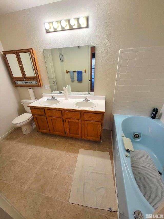 bathroom with tile patterned floors, a bathing tub, vanity, and toilet