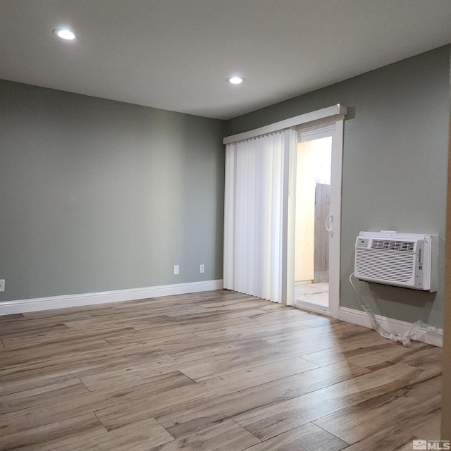 empty room with light wood-type flooring and a wall mounted AC