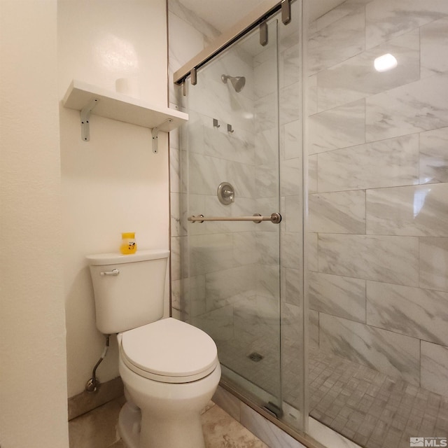 bathroom featuring toilet and a shower with door