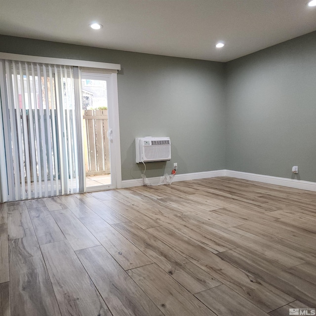 unfurnished room with light wood-type flooring and a wall mounted AC