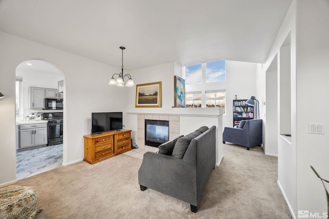 carpeted living room featuring a tile fireplace and an inviting chandelier