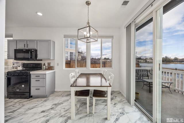 kitchen featuring tasteful backsplash, pendant lighting, gray cabinets, a water view, and black appliances