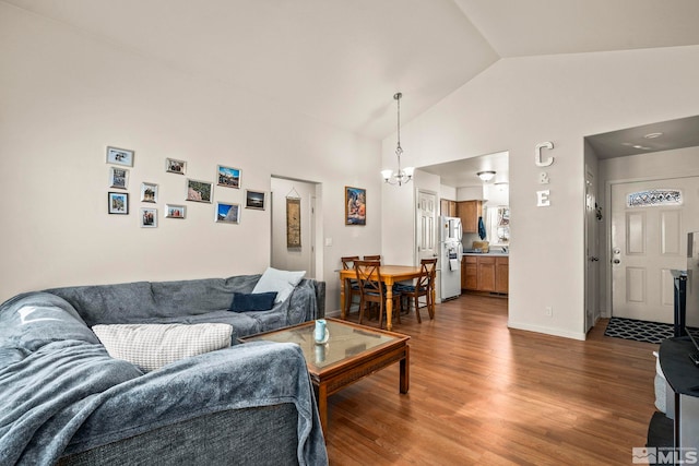 living room with hardwood / wood-style floors, high vaulted ceiling, and a notable chandelier