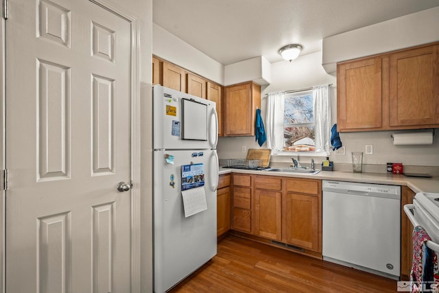 kitchen featuring a textured ceiling, white appliances, sink, and light hardwood / wood-style flooring