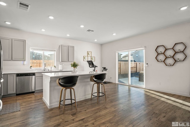 kitchen featuring dark hardwood / wood-style floors, a center island, a kitchen breakfast bar, and dishwasher