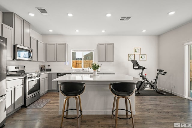 kitchen featuring sink, gray cabinets, stainless steel appliances, dark hardwood / wood-style floors, and a center island