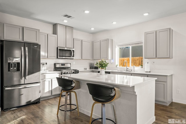 kitchen featuring sink, dark wood-type flooring, appliances with stainless steel finishes, a kitchen breakfast bar, and a center island