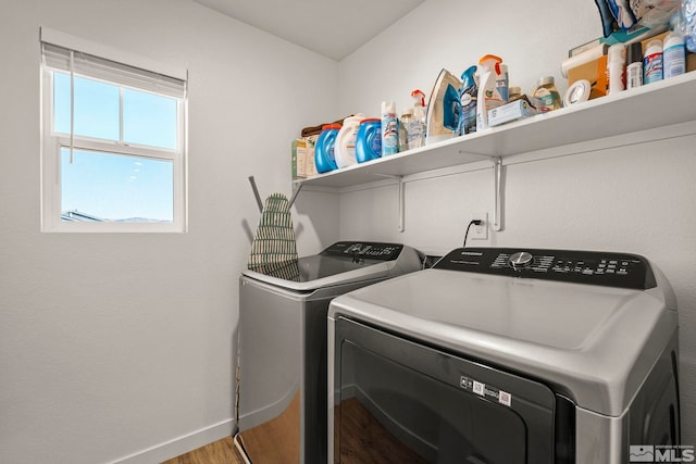 clothes washing area with washing machine and dryer and wood-type flooring